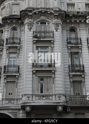 Homme marchant sur les trottoirs avec des sacs de shopping en fin d'après-midi en face de San Telmo bar avec peinture en noir et blanc de l'homme à l'entrée du mur. Banque D'Images