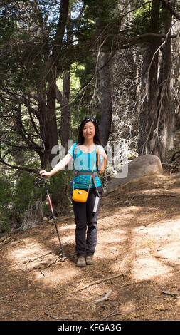 Young Asian female hiker debout en train de section pommelé sun wearing blue shirt, pantalon noir Michael Kors en cuir jaune petit sac en cuir jaune Banque D'Images