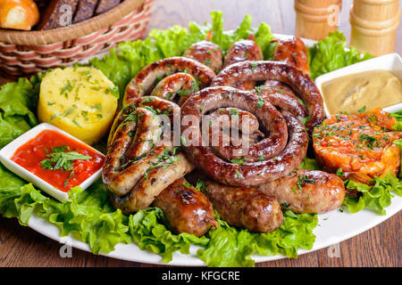 Un assortiment de saucisses bavaroises garnie avec les verts et les sauces Banque D'Images