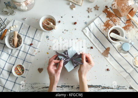 Femme arcs de liens sur le cadeau de Noël avec un ruban bleu. maison de vacances concept. vue d'en haut. Banque D'Images