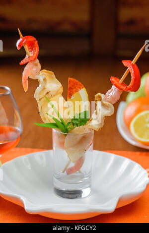 Fruits de mer grillés sur les bâtonnets dans un plat shell décoratif Banque D'Images