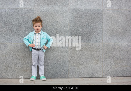 Fashion kid posant près de mur gris Banque D'Images