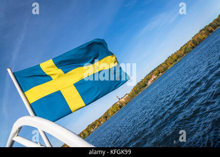 Drapeau suédois sur un bateau et l'île de Djurgarden en arrière-plan, Stockholm, Suède Banque D'Images