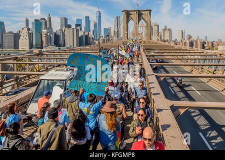 New York, États-Unis. 28 octobre 2017. Des milliers de New-Yorkais se sont réunis pour le #Sandy5 mars le 28 octobre 2017 pour commémorer le cinquième anniversaire de la grande tempête Sandy. En traversant le pont de Brooklyn par une vague bleue, les participants exigent une action puissante sur le climat de la part des élus de New York. Plus de 150 organisations locales, nationales et nationales, avec une forte représentation des quartiers touchés par la tempête, ont signé la marche. Crédit : Erik McGregor/Pacific Press/Alay Live News Banque D'Images