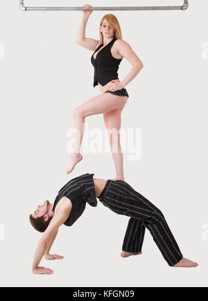 Jeune couple équilibre acrobatique pratiques avec femme debout sur le ventre de l'homme. Banque D'Images