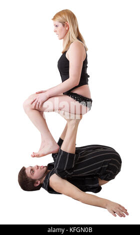 Jeune couple avec équilibre acrobatique pratiques femme assise sur l'homme en son upstretched les jambes. Banque D'Images