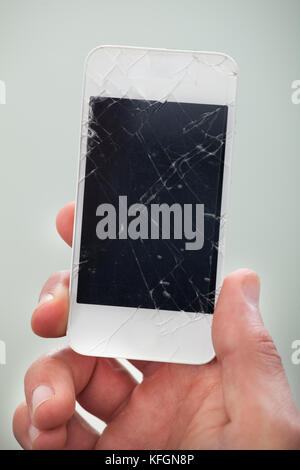 Businessman holding a endommagé smartphone avec un écran brisé dans sa main de l'afficher à la caméra Vue en gros Banque D'Images