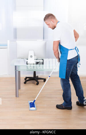 Beau mâle nettoyeur ou le nettoyage du filtre à l'étage dans un immeuble de bureaux à l'aide d'un RDP pour laver et désinfecter la surface de la Banque D'Images