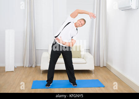 Young happy man exercising on exercise mat Banque D'Images