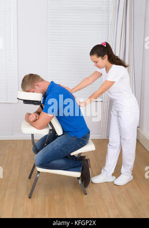 Photo de jeunes femelles de l'épaule de masseur massaging man Banque D'Images