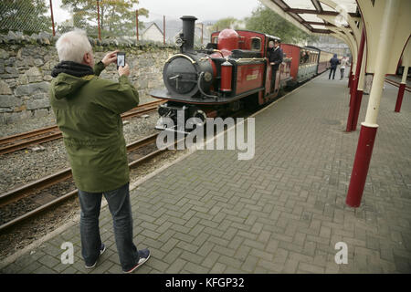 Man using smartphone pour photographier près de locomotive à vapeur à Blaenau Ffestiniog Ffestiniog station sur la voie étroite, le Pays de Galles. Banque D'Images