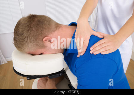 Photo de femme l'épaule physiothérapeute massaging man Banque D'Images