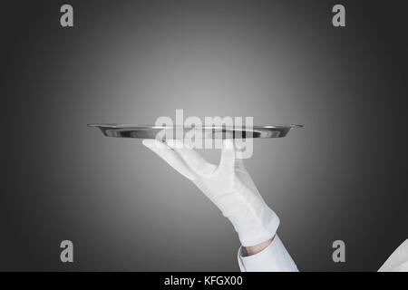 Portrait of waiter holding tray sur fond gris Banque D'Images