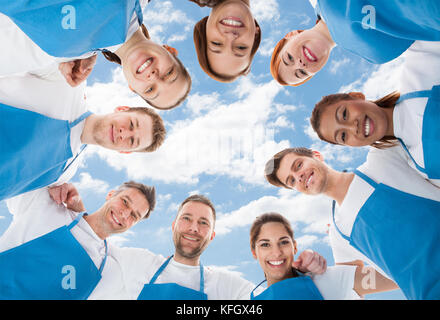 Directement au-dessous tourné de nettoyeurs professionnels divers standing in huddle against sky Banque D'Images