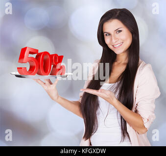 Portrait de belle femme présentant 50% de réduction sur plateau sur fond coloré Banque D'Images