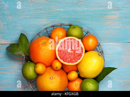 Un demi-pamplemousse et autres agrumes : citron, mandarine, orange, citron vert, bleu sur un kumquat fond de bois Banque D'Images