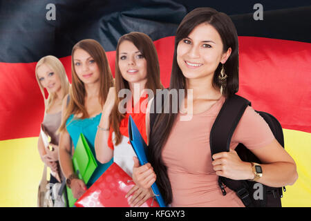 Groupe d'happy college students standing in front of German flag Banque D'Images