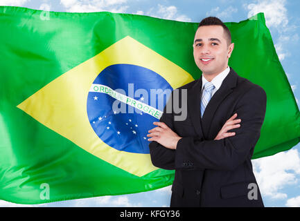 Portrait of young businessman standing in front of Brazilian flag Banque D'Images