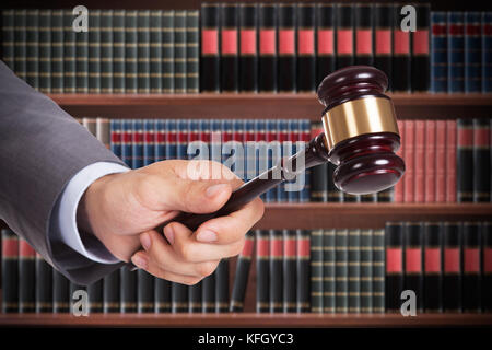 Main de juge mâle frappant le Gavel en bois dans Une salle d'audience Banque D'Images