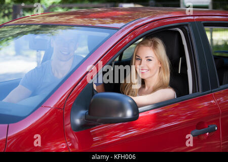 Portrait of happy young woman with man sitting in new car Banque D'Images