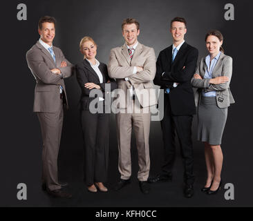 Portrait of confident business team standing les bras croisés sur fond noir Banque D'Images