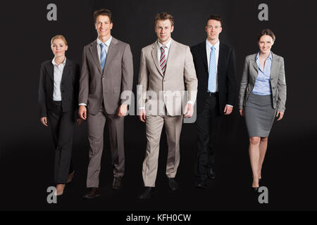 Full Length portrait of business people walking sur fond noir Banque D'Images