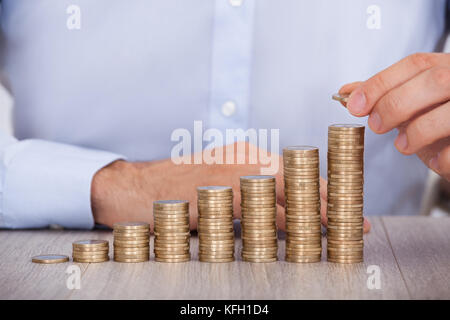 Portrait of businessman empiler des pièces en euros à l'office de tourisme 24 Banque D'Images