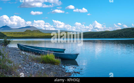 Deux canoës bleu sur le bord d'un lac calme avec de vertes collines en arrière-plan Banque D'Images