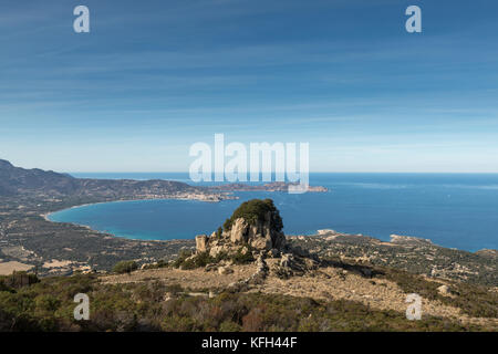 Les arbres croissant sur un éperon rocheux dans les collines au-dessus du village abandonné d'occi près de Lumio en balagne de corse avec la citadelle de calv Banque D'Images