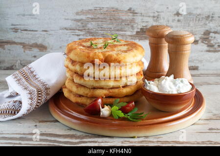 Tortillas de pommes de terre poêlées servies avec sauce au yogourt et des légumes frais. Banque D'Images