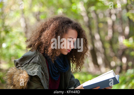 Voir à teen girl reading book in autumn park Banque D'Images