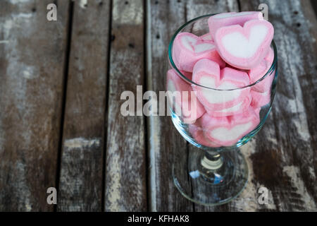 Guimauves en forme de coeur en verre sur un plancher en bois. Banque D'Images