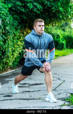 Un homme dans le parc dans le cadre d'un échauffement. Écoute de la musique pour une promenade dans la ville. Athletic mode de vie. Banque D'Images