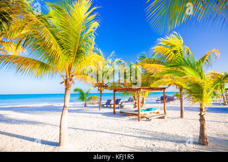 Des chaises longues sous un parasol sur la plage de sable Banque D'Images