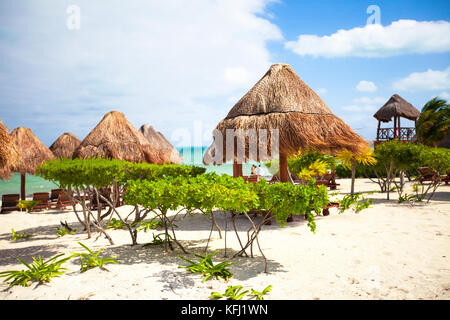 Des chaises longues sous un parasol sur la plage de sable Banque D'Images