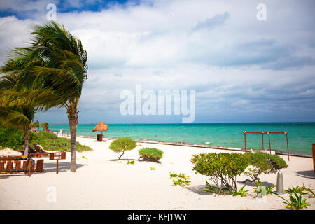 Des chaises longues sous un parasol sur la plage de sable Banque D'Images