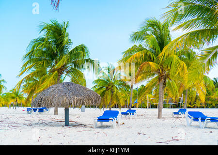 Des chaises longues sous un parasol sur la plage de sable Banque D'Images