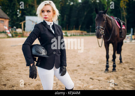 Jeune femme avec casque, pose les mains contre le cheval, l'équitation. brown stallion, loisirs avec animal, sport équestre Banque D'Images