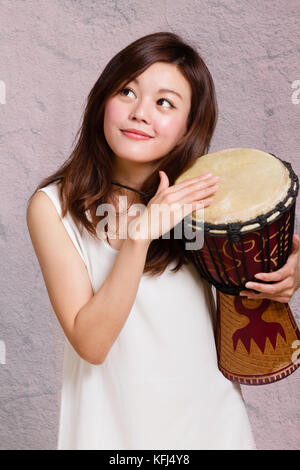 Asian American Woman playing djembe africain tambour à main Banque D'Images