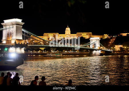 Vue sur le château de Buda Budapest avec la chaîne link bridge Széchanyi Lánchid et du Danube, dans l'avant-plan ; prises de nuit Banque D'Images