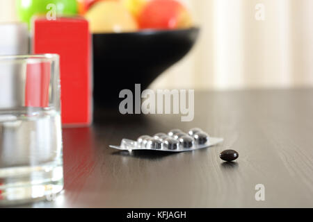 Close up d'un complexe de vitamines comprimés sur une table avec des fruits à l'arrière-plan Banque D'Images