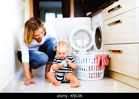 Jeune maman avec un petit garçon à faire des travaux ménagers. Banque D'Images