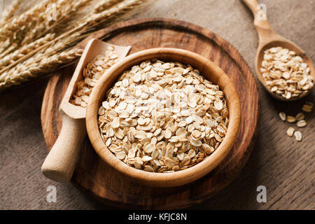 Les flocons d'avoine, flocons d'avoine bio en bol en bois et les épis de blé d'or sur fond de bois. mode de vie sain, une alimentation saine, la nourriture végane concept Banque D'Images