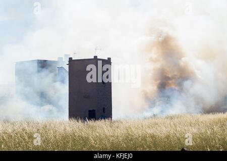 Ancienne tour de telegraph entouré avec du blé avec un petit feu et la fumée faisant quelque chose de semblable à un visage Banque D'Images