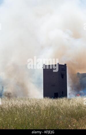 Ancienne tour entouré avec du blé et avec de la fumée d'un petit incendie Banque D'Images