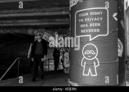 Street art poster accroché sur un tunnel près de la colonne de l'artiste subdude avec homme stylisé et cartoon avec slogan "Votre droit à la vie privée a été révoquée". Banque D'Images