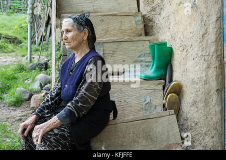 Province de Gilan- IRAN-Mai 10, 2017 Femme assise sur les marches de bois et satre à l'extérieur du châssis en tissu traditionnel Banque D'Images