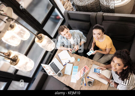 Heureux l'homme et de la femme à l'aide de leurs téléphones tout en travaillant Banque D'Images