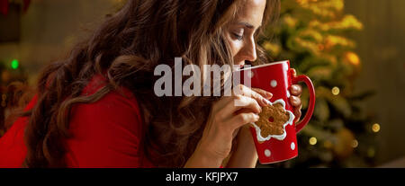 Biscuits de Noël sont une façon merveilleuse de profiter de l'esprit de la saison. heureux jeune femme ayant une tasse de chocolat chaud avec des guimauves et cookie dans Banque D'Images