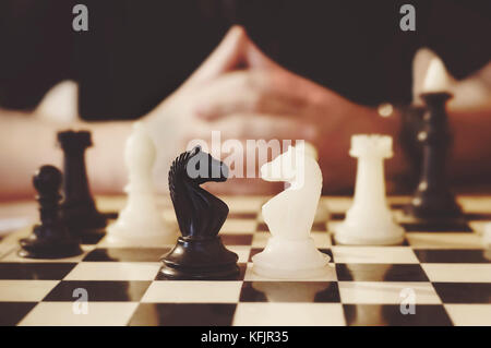Jeune homme jouant aux échecs. traversé la main floue en arrière-plan. Banque D'Images
